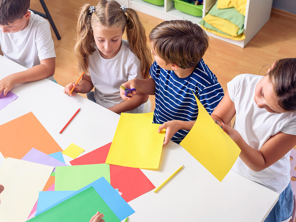 group of young kids cutting colorful paper