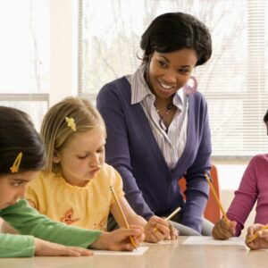 teacher looking on as her students work