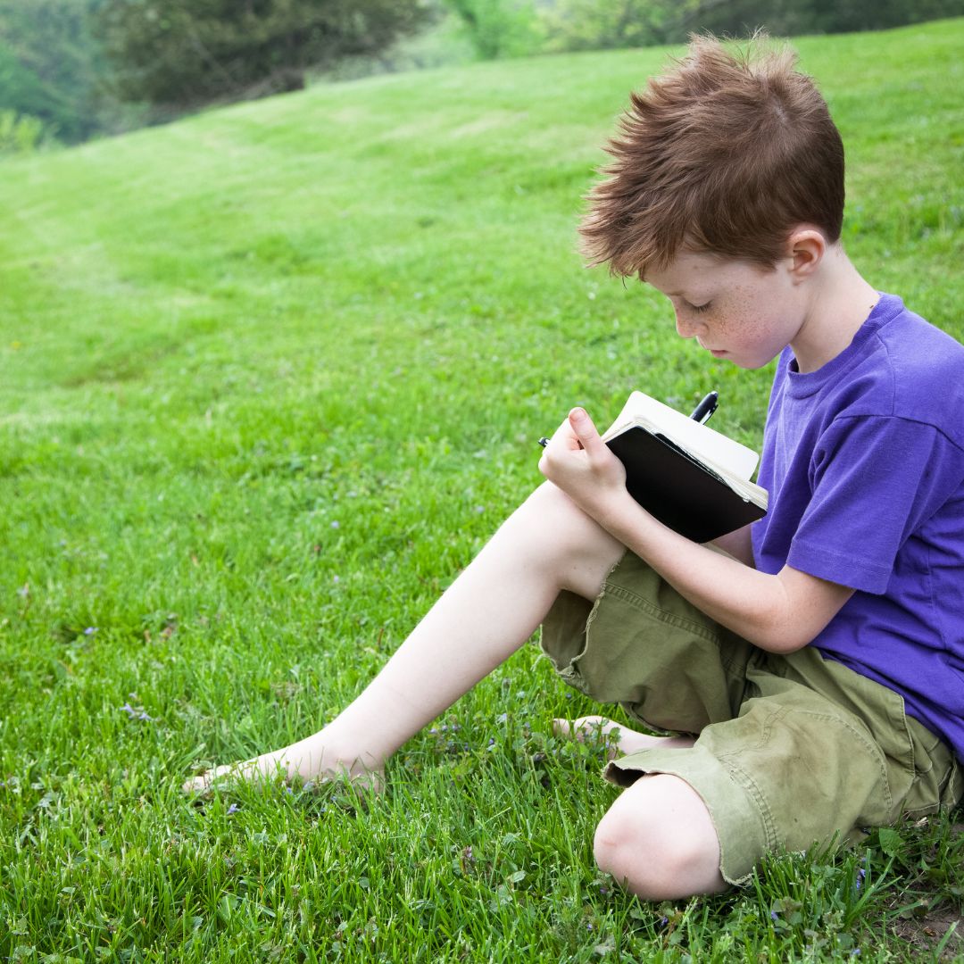 young boy writing in a journal