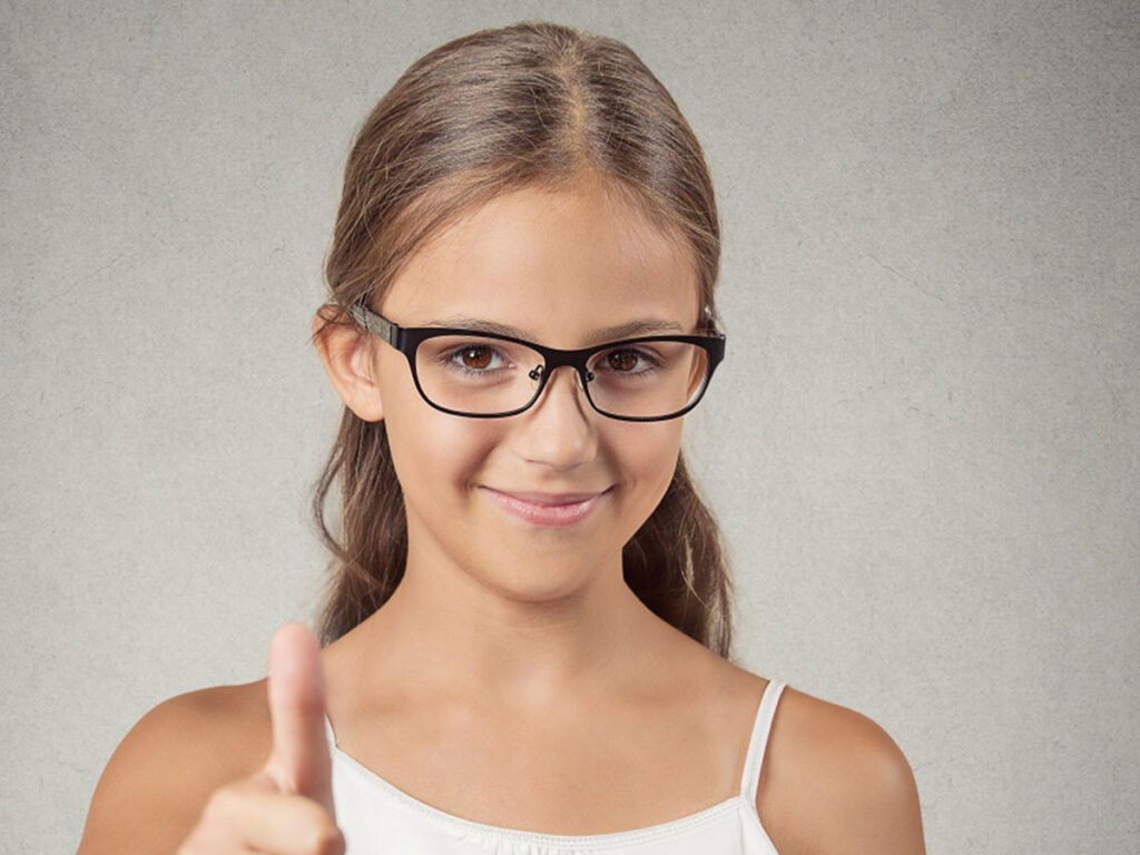 Image of a young girl wearing glasses putting her thumb up.