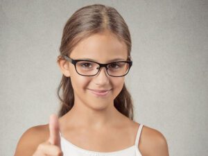 Image of a young girl wearing glasses putting her thumb up.